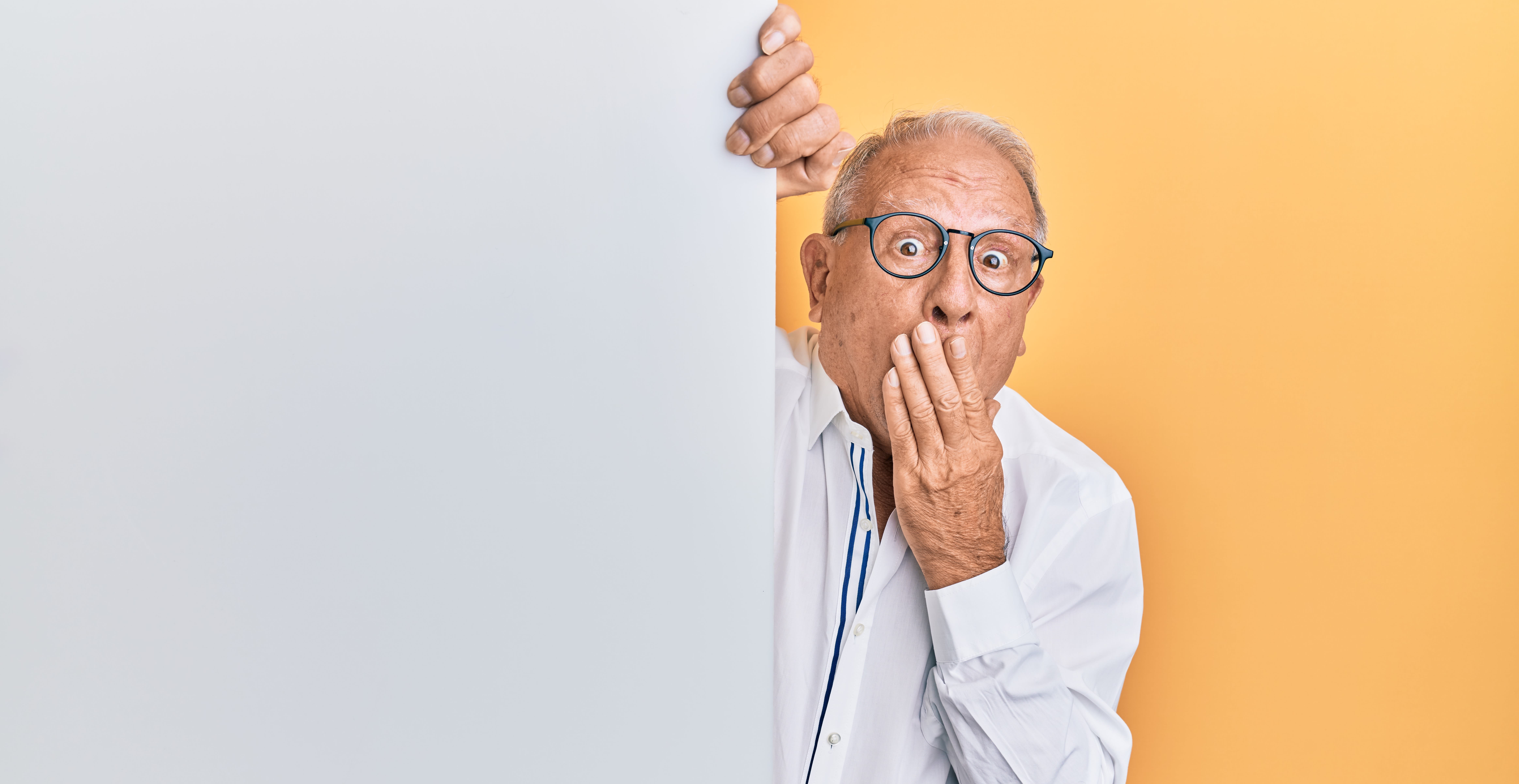 An old man with glasses covering his mouth in surprise.