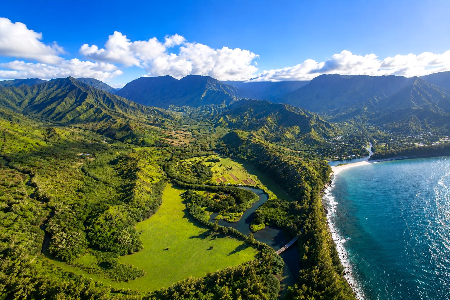 An aerial view of a green river valley winding toward the coast