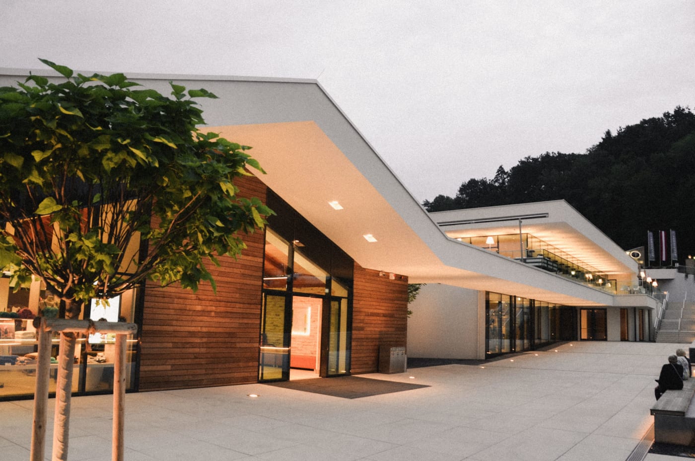 A entrada do Heiltherme de Bad Waltersdorf ao anoitecer, arquitetura branca e madeira