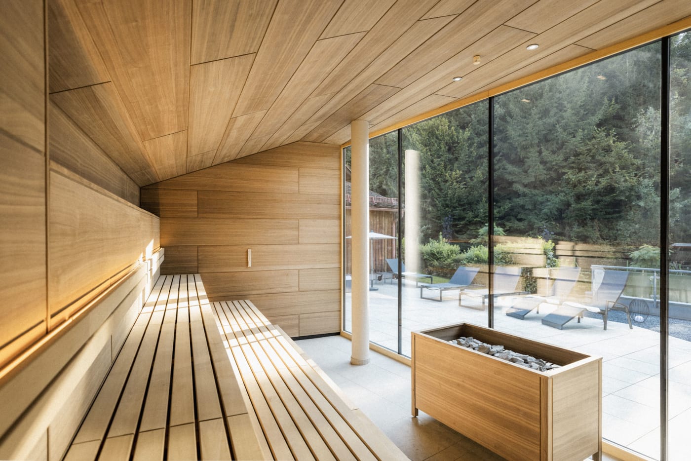 Uma sauna de madeira do Hoteltherme com uma grande janela panorâmica para o terraço de descanso