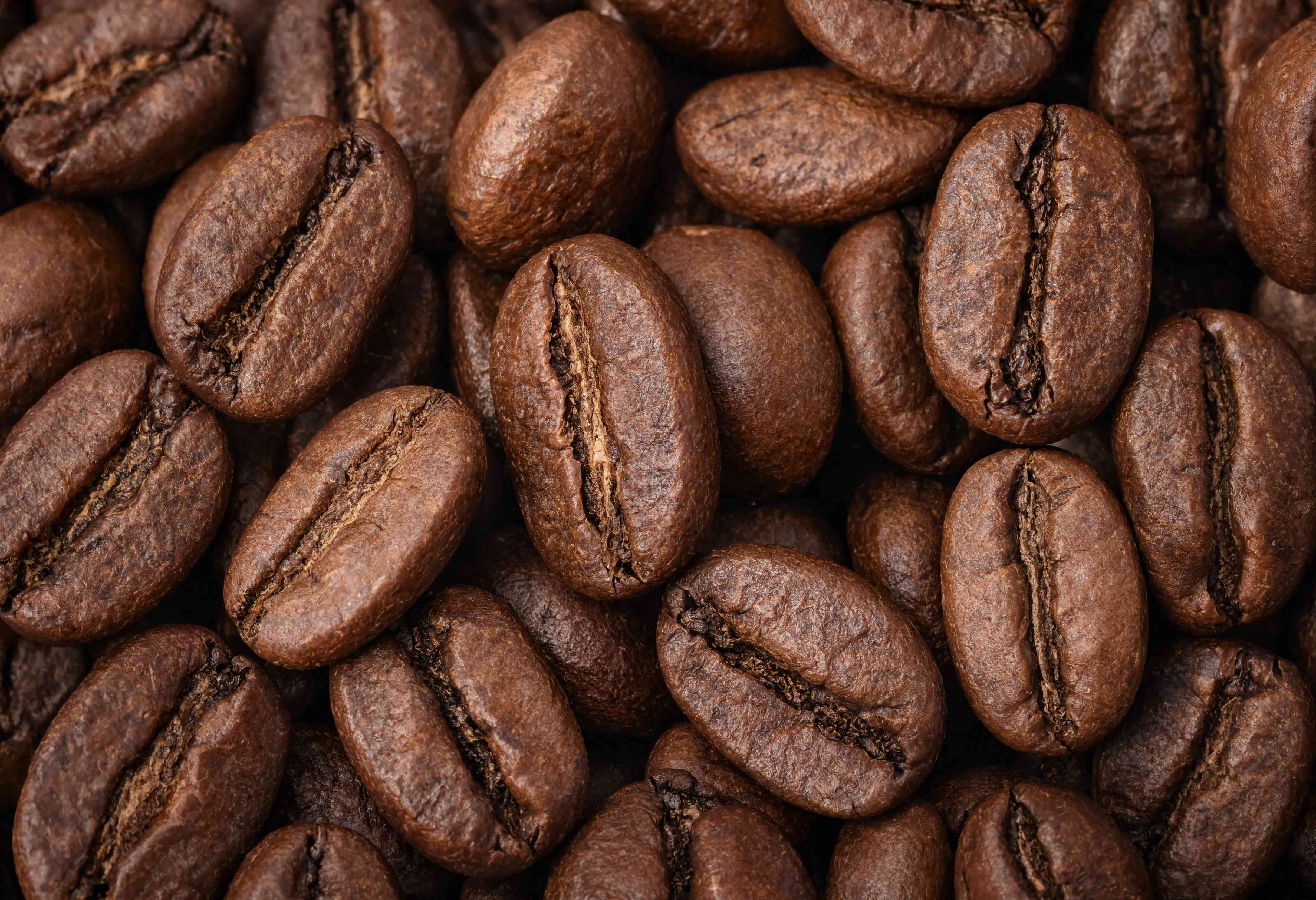 Macro rất gần nhiều hạt cà phê rang Arabica, hạt nâu bóng với rãnh rõ