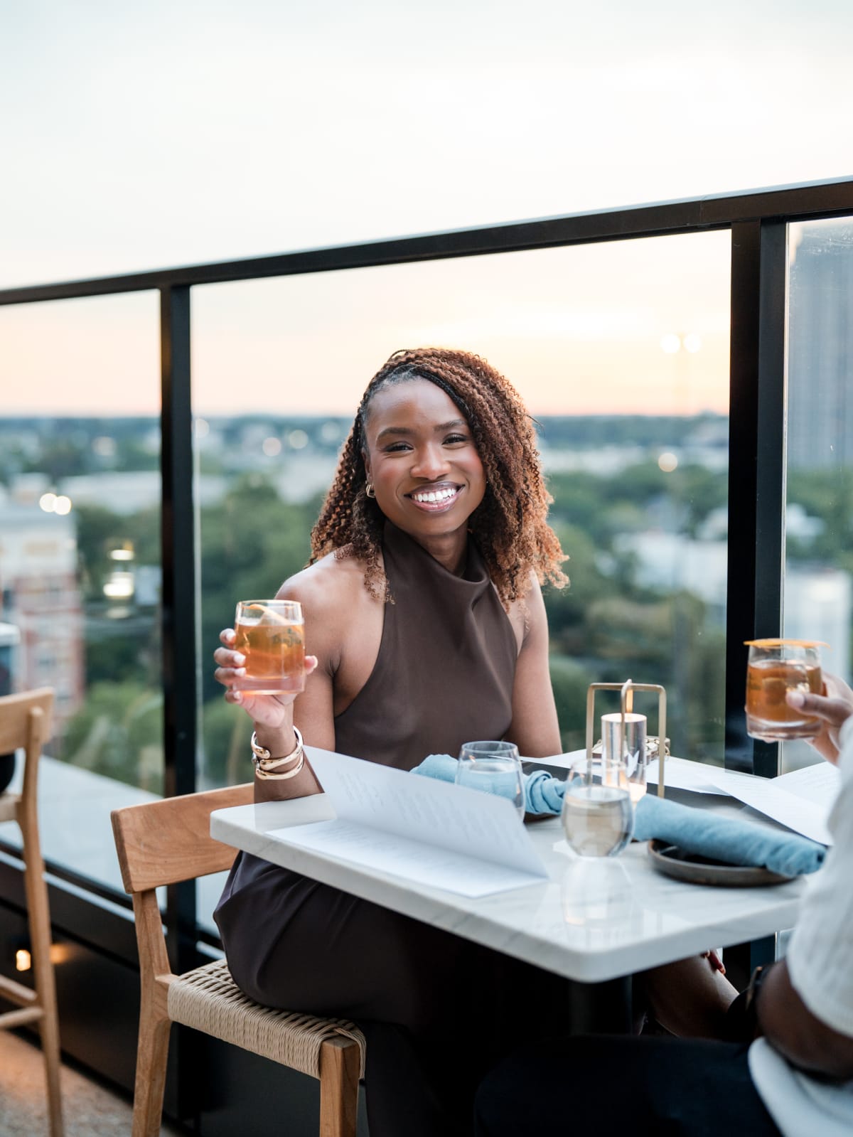 Guest seated at a window table with the city behind