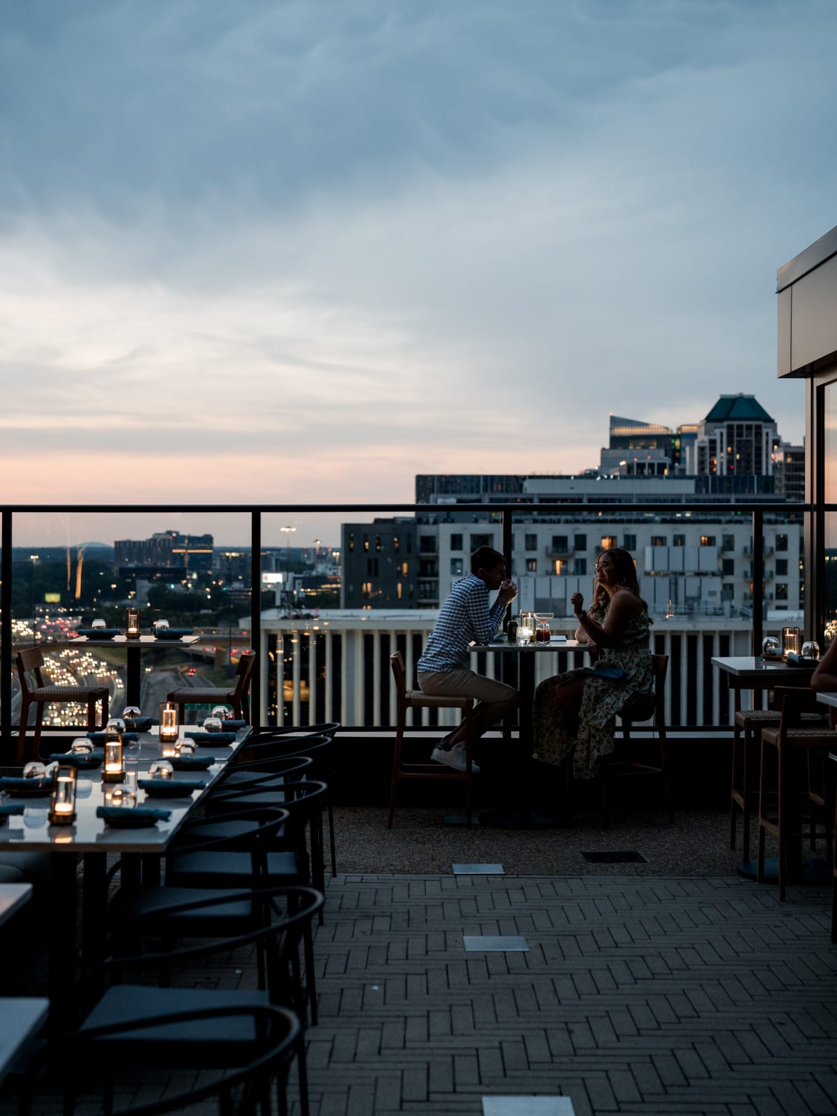 Rooftop tables at dusk with the skyline behind