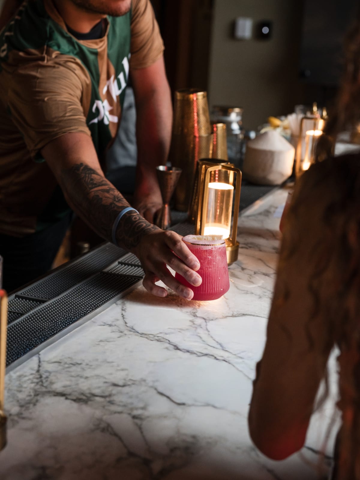 Bartender placing a finished cocktail on the bar