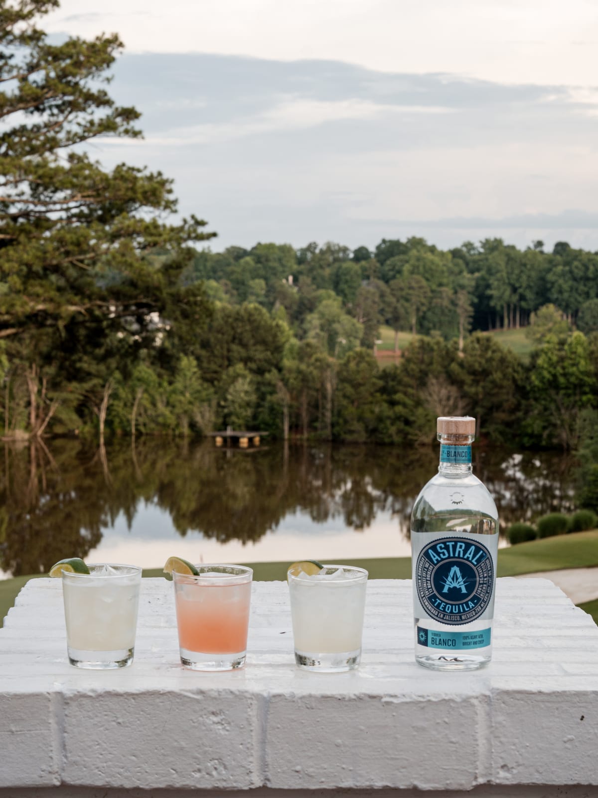 Astral bottle and a row of cocktails overlooking the lake