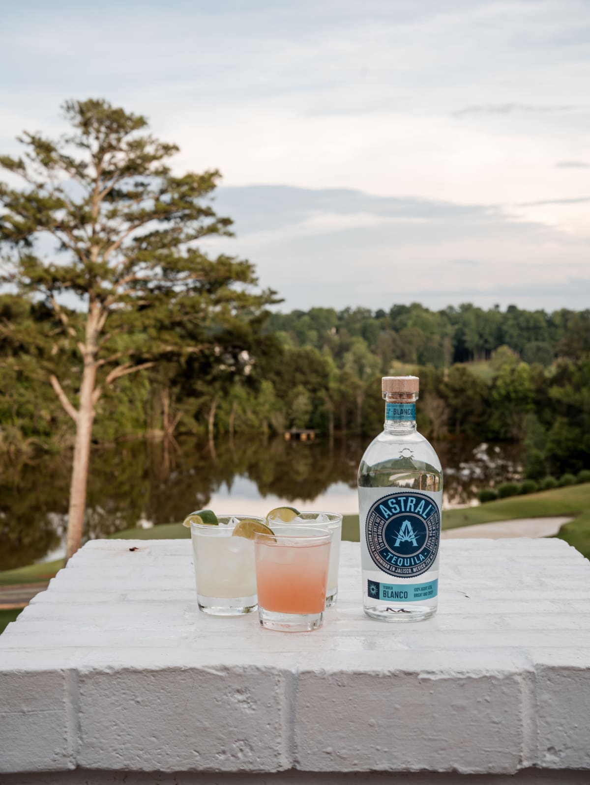 Astral bottle with two cocktails on the ledge at sundown