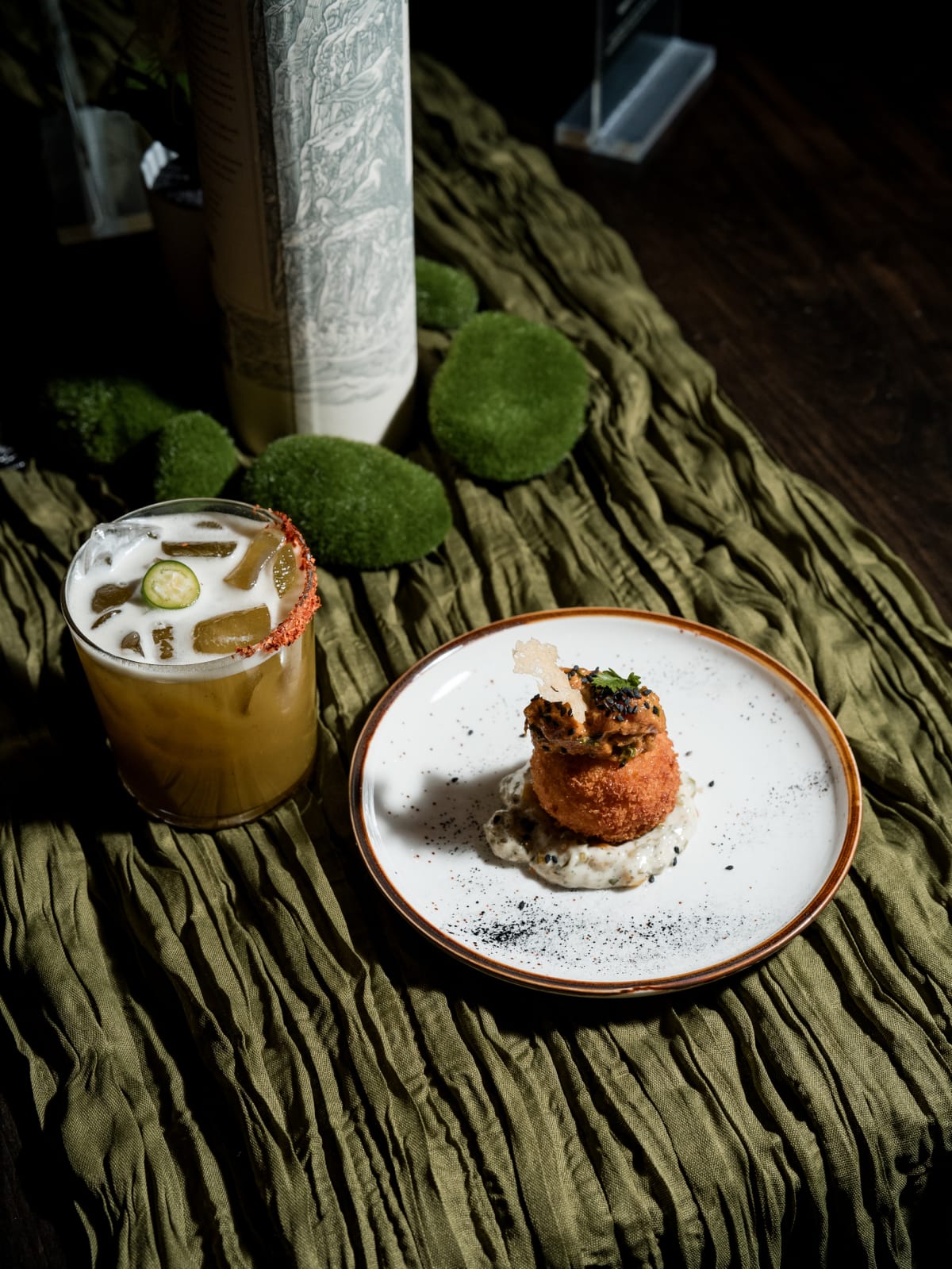 Highball and a plated bite on the olive runner
