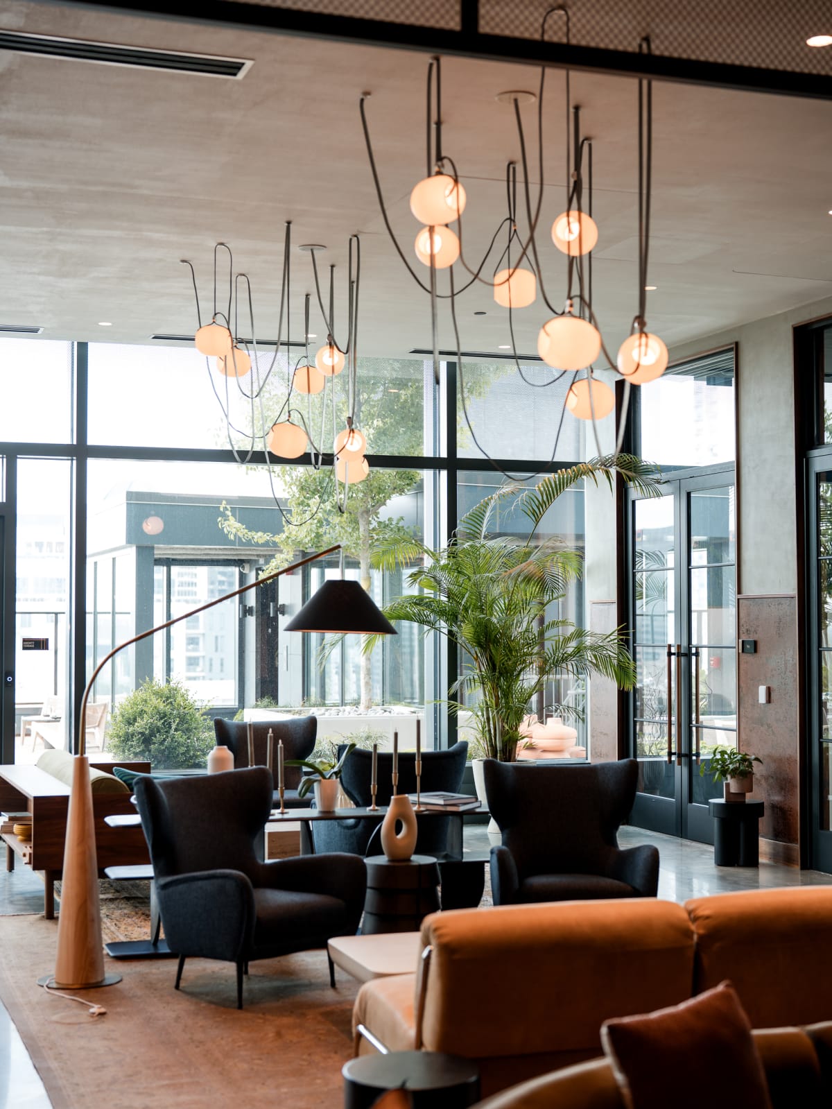Sculptural chandeliers over armchairs at the window wall