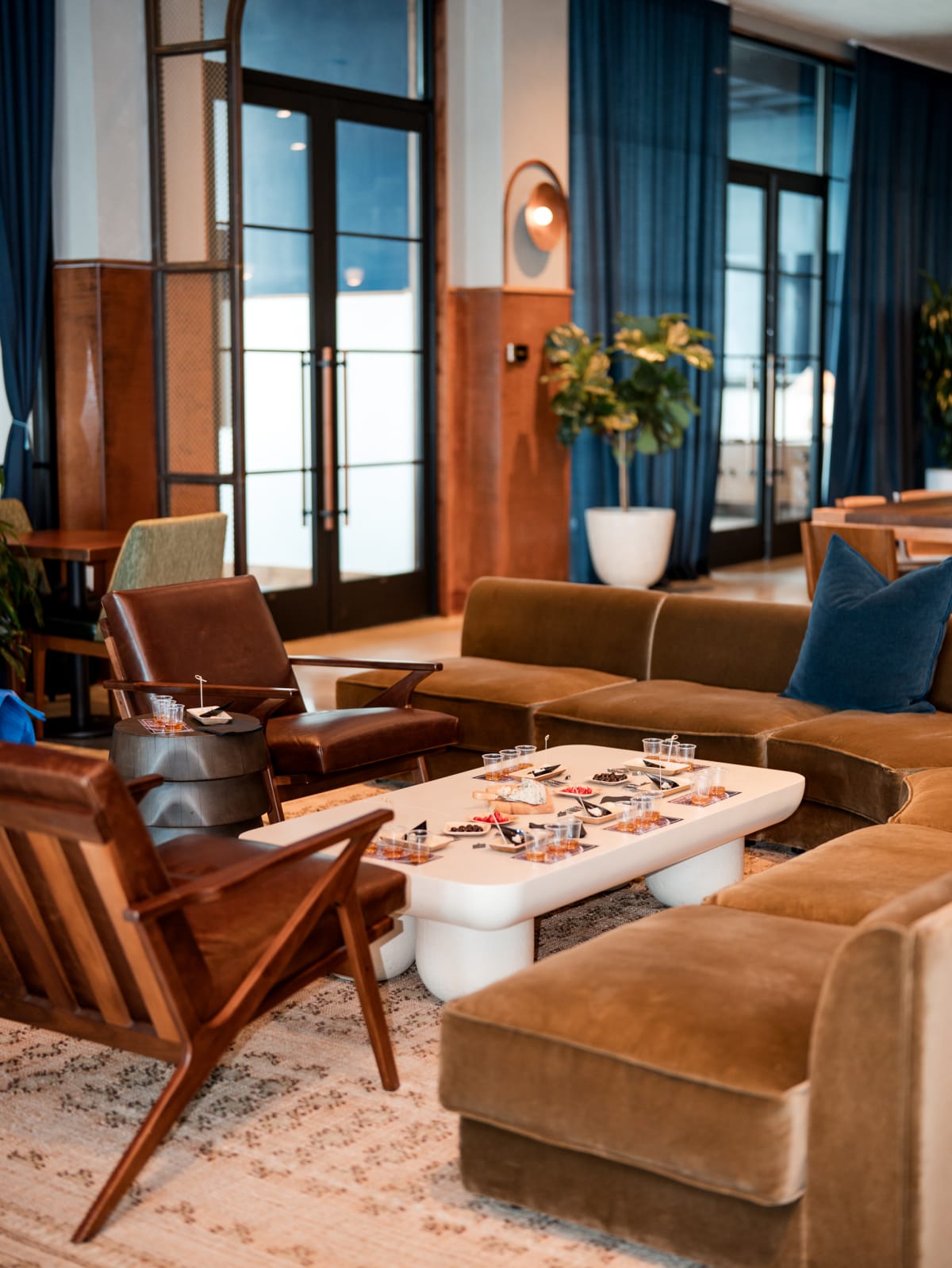 Velvet lounge seating set for guests beneath blue curtains