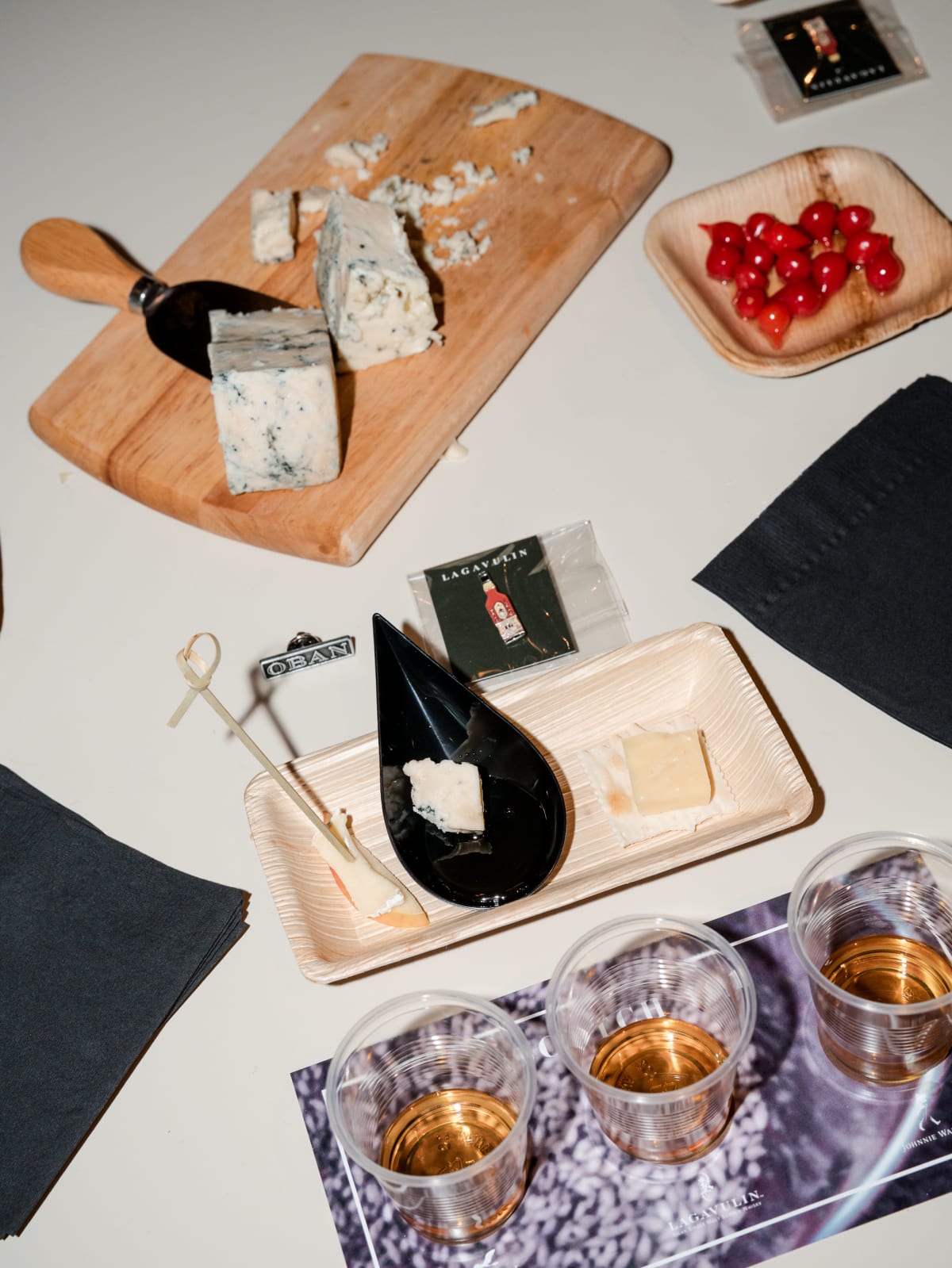 Overhead pairing board with cheese, olives, and three drams