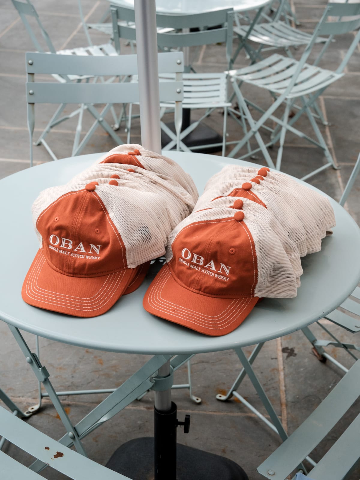 Branded Oban caps and towels set out on a patio table