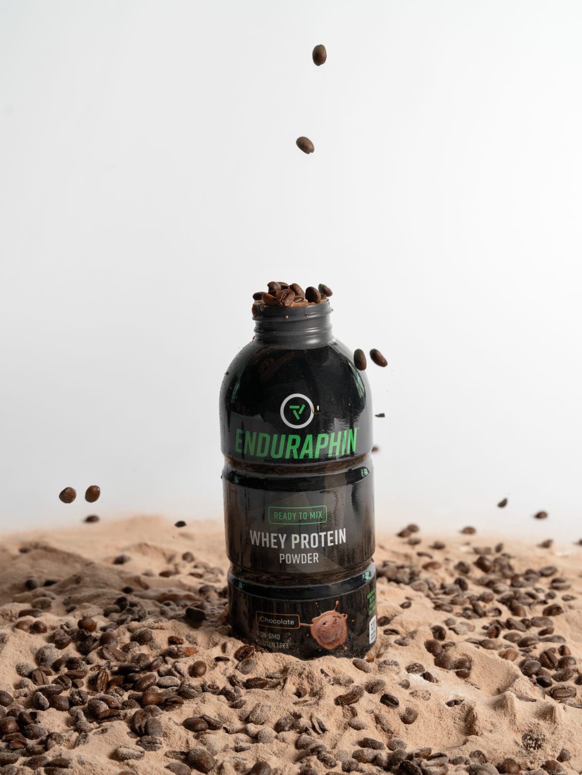 Enduraphin coffee bottle standing in a bed of beans