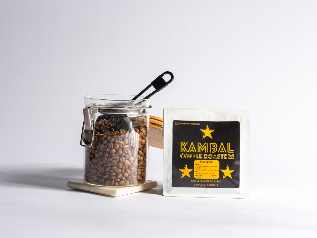 Kambal bag beside an open jar of whole beans