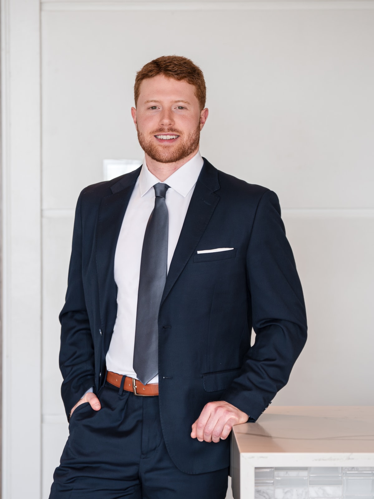Three-quarter portrait leaning on a stone counter in an office lobby