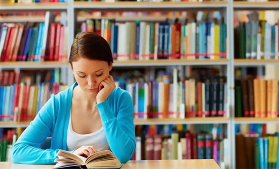 Wanita Membaca Buku di Perpustakaan