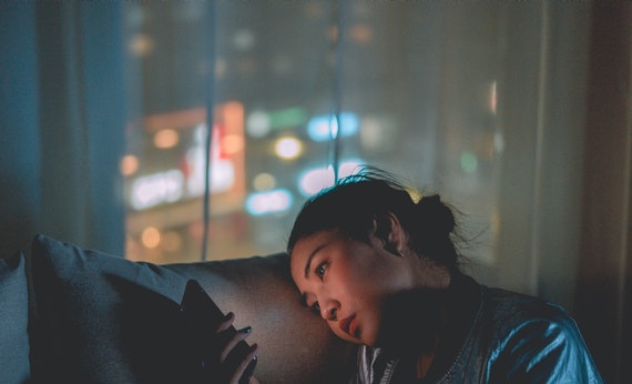 Wanita melihat handphone sedang menjalani long distance relationship