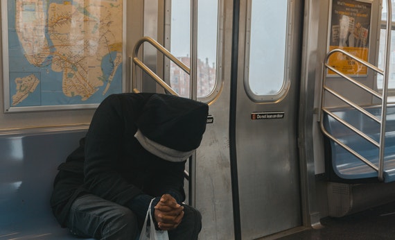 Pria memakai hoodie sedang menunduk di kereta