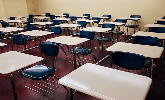 kursi kelas berwarna hitam dan meja kelas berwarna putih