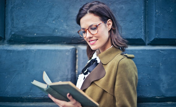 Woman in brown suede peacoat reading a book