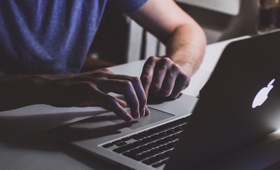 Pria sedang membuka Laptop Macbook