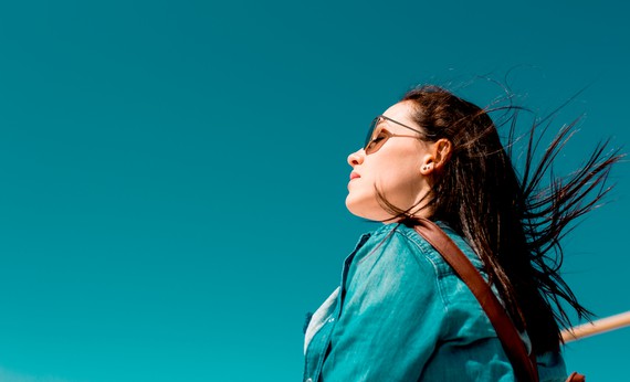 Wanita memakai kacamata dan jaket warna tosca
