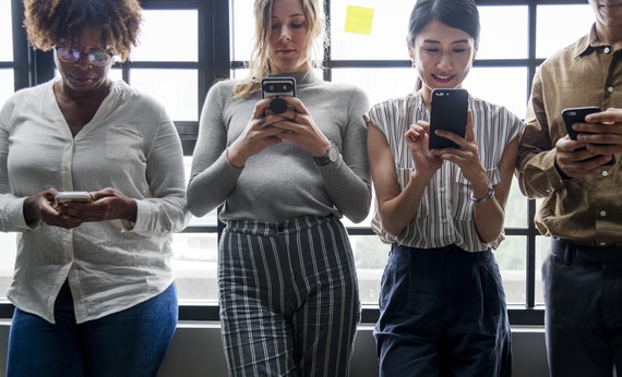 Empat orang sedang melihat smartphone secara bersamaan