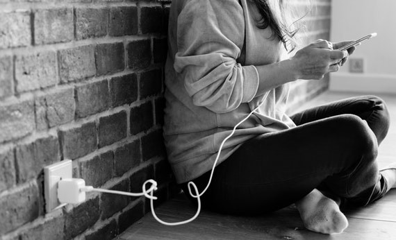 Orang sedang menggunakan smartphone yang sedang di charger