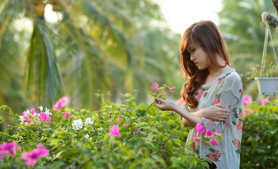 Wanita sedang memegang bunga di taman