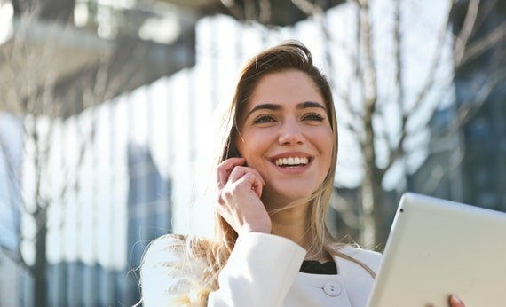 Wanita sedang membawa tablet iPad sambil tersenyum