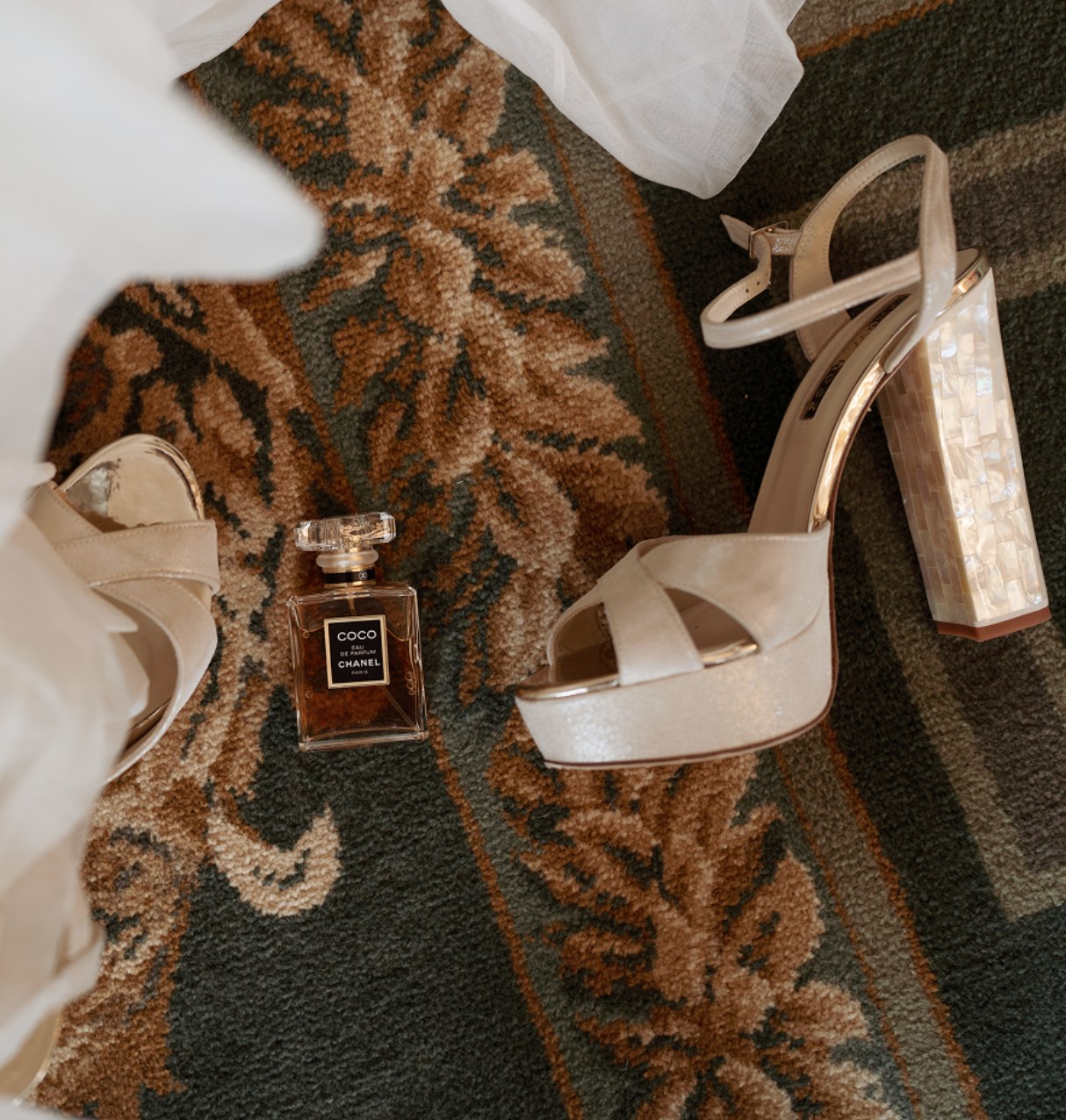 Wedding accessories - a bottle of perfume and a high heel on the floor