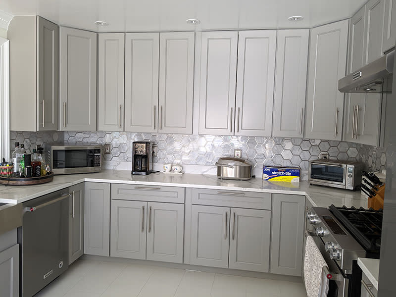 Run of grey shaker base and wall cabinets with quartz counters and a marble hexagon backsplash