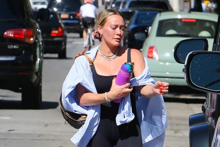 A person holding a purple and blue water bottle