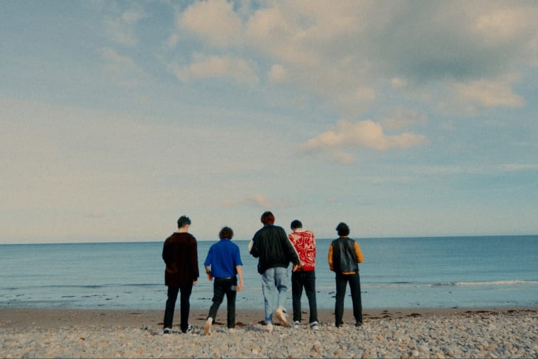 five young people standing on a beach