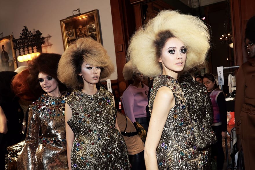 A women with big hair, large eyelashes and shiny dress