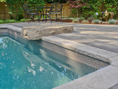 Natural stone pool coping with inset jumping rock.