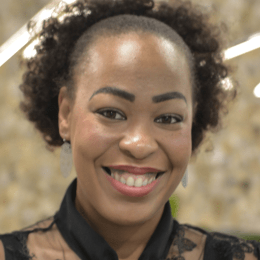 Person smiling warmly in a professional setting with soft background lighting
