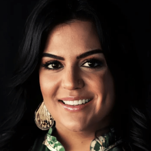 Portrait of a smiling woman with dark hair, wearing large earrings and a patterned top