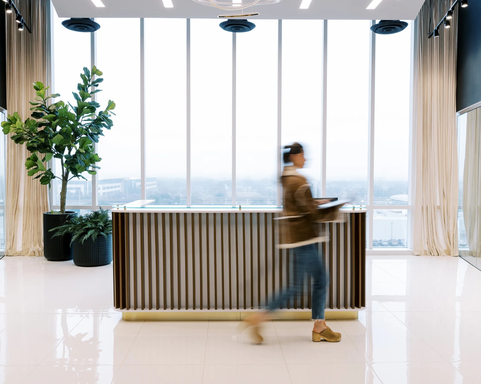 Woman walking past the reception desk at Lucid Private Offices - West Plano / Willow Bend
