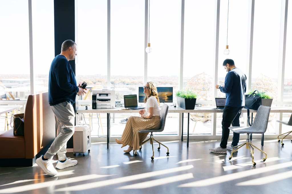 Members working and socializing in a sunlit Lucid Private Offices open coworking space with panoramic views