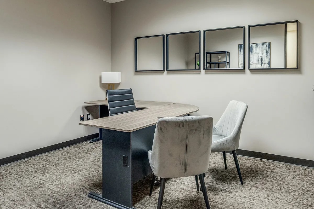 Small private office at Lucid Private Offices Dallas Galleria with L-shaped desk, mirrors, and guest chairs