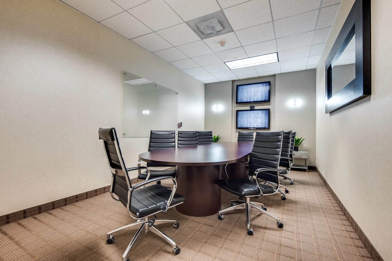 Lucid Private Offices Dallas Galleria meeting room with round conference table, executive chairs, and dual display screens