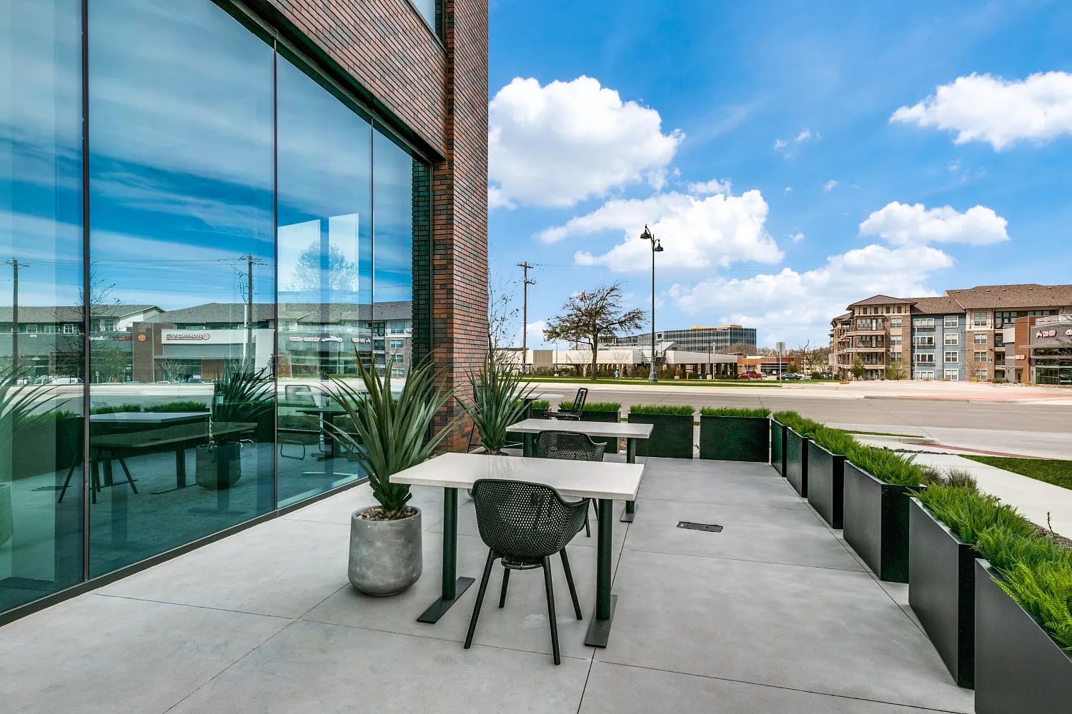Outdoor terrace at Lucid Private Offices McKinney with patio seating, tables, and sunny sky view