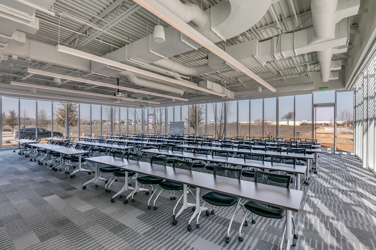 Large training room with rows of seats and desks, industrial ceiling, and panoramic windows