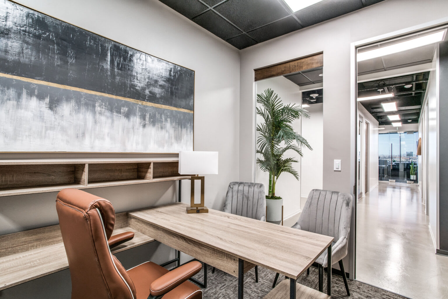 Private office lounge with conference table, leather chairs, and large canvas wall art