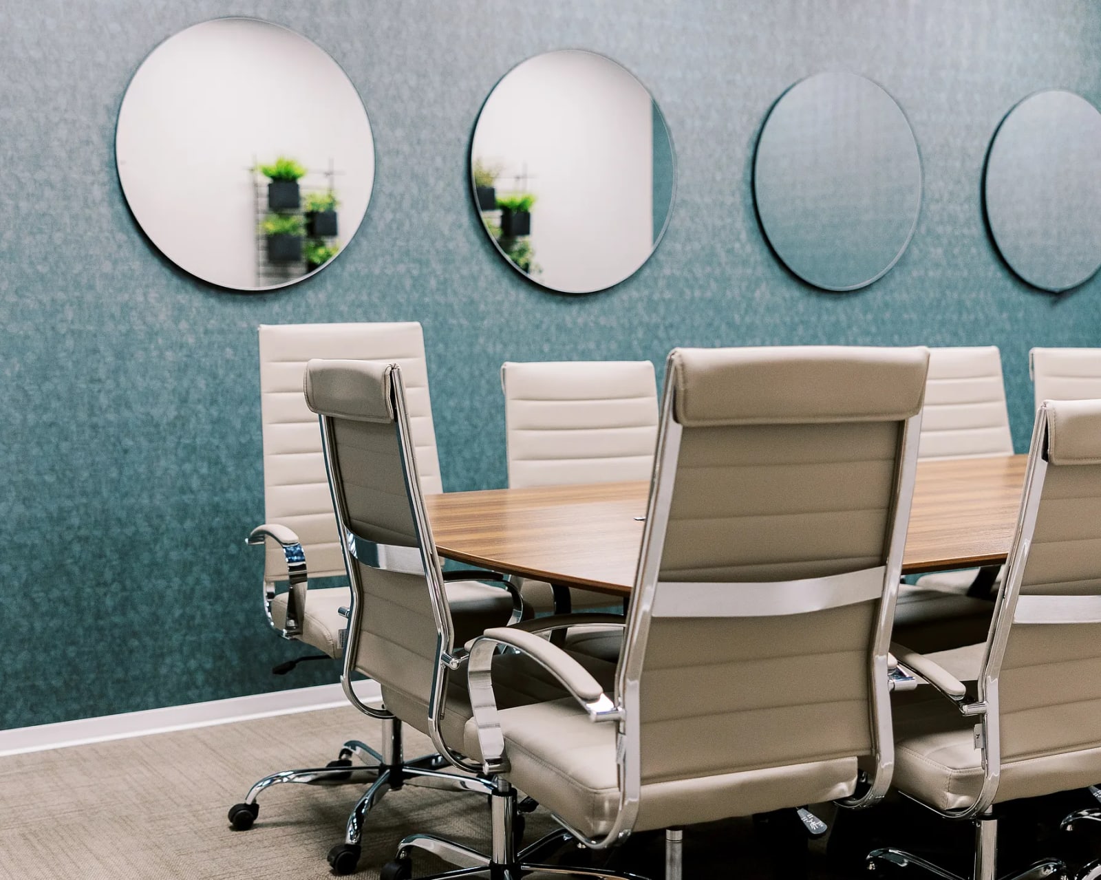 Meeting room with teal accent wall, circular mirrors, and conference table with chairs