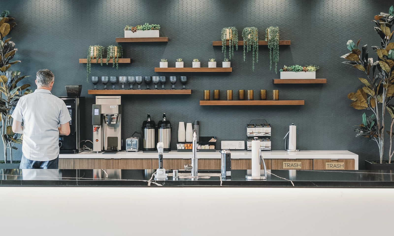 Lucid Private Offices member coffee bar with pour-over station, curated glassware, and floating shelves of greenery.