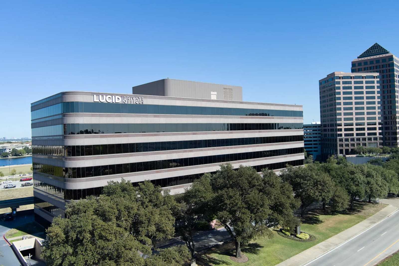 Lucid Private Offices Las Colinas building exterior with parking area and trees