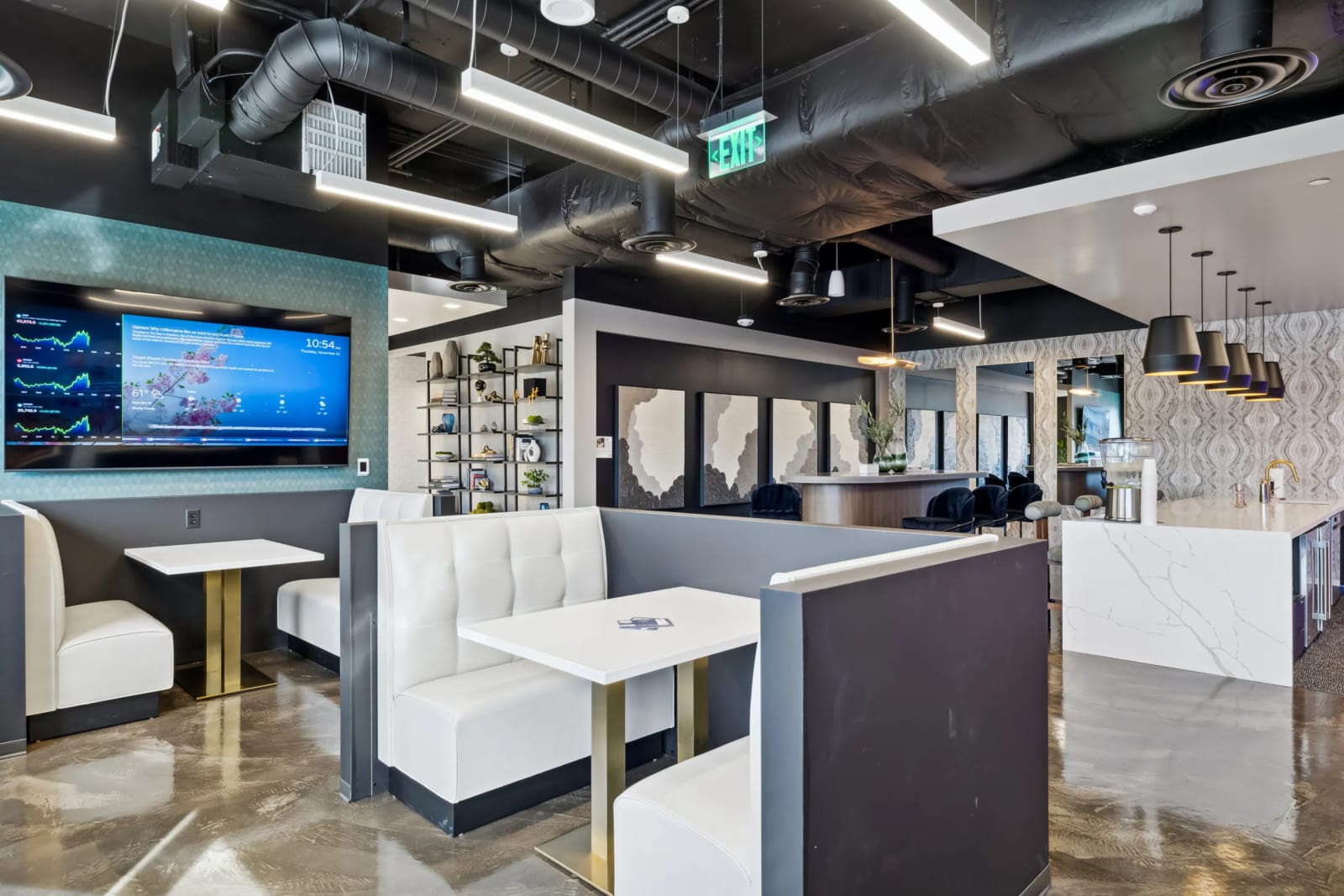 Coworking lounge at Lucid Private Offices Kierland with white booth seating, industrial ceiling, and large screens