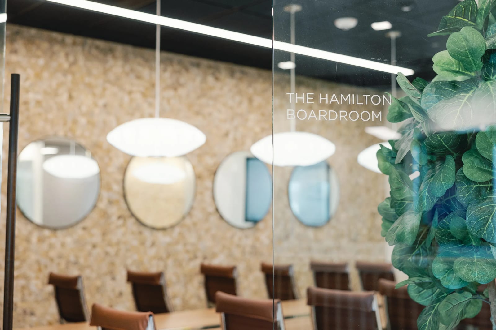 Meeting room at Lucid Private Offices McKinney with globe pendant lights, slatted walls, and modern seating