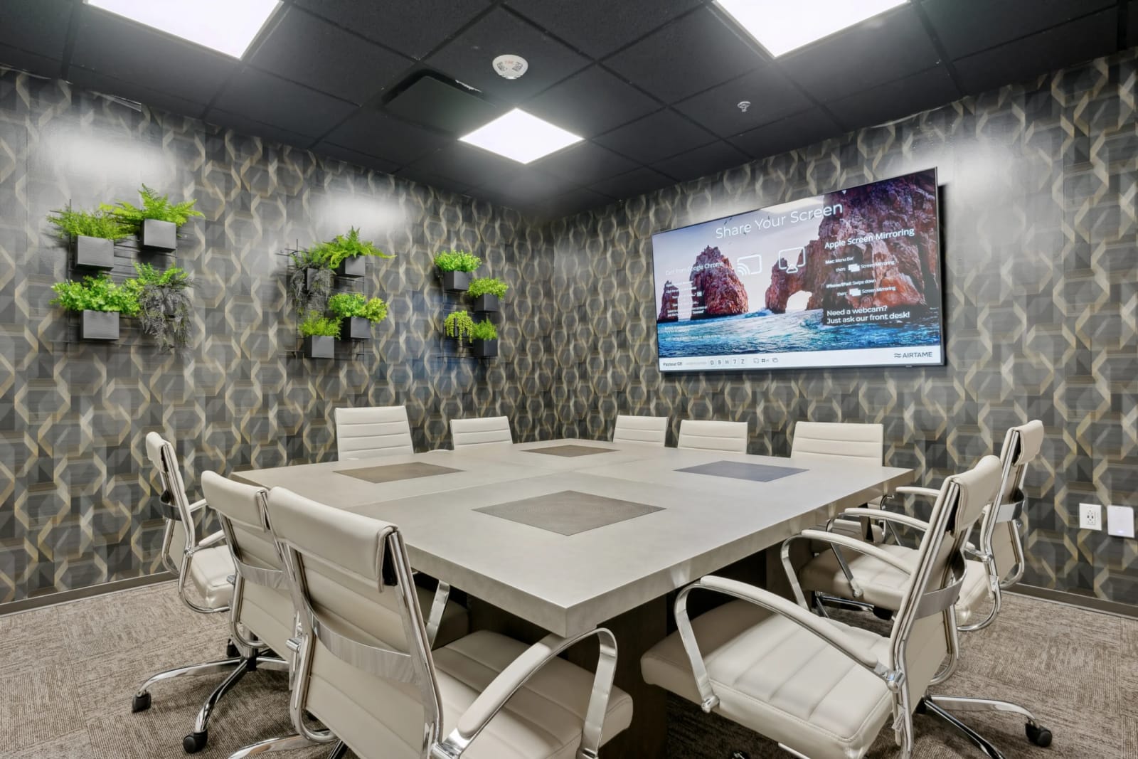 Modern boardroom with conference table, TV screen, and decorative wall panels at Lucid Private Offices
